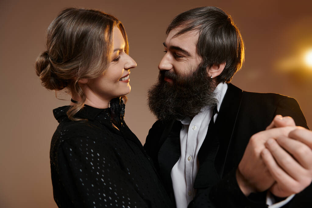 Un hombre y una mujer vestidos con elegante atuendo se miran amorosamente. - Foto, imagen