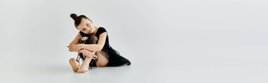 Una joven con una pierna protésica se sienta en el suelo de un estudio. - Foto, Imagen