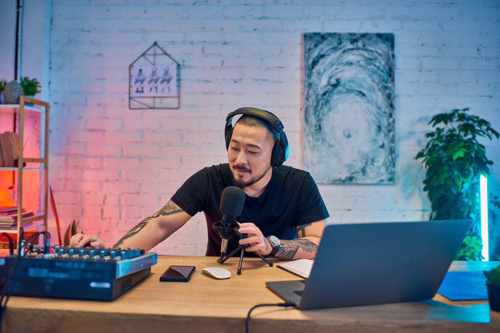 Un hombre asiático guapo grabando un podcast en su colorido estudio. - Foto, Imagen