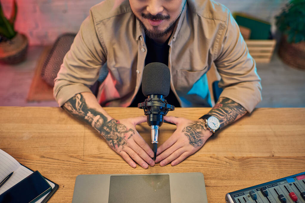 Egy tetovált ázsiai férfi ül a podcast stúdiójában, készülve a felvételre. - Fotó, kép