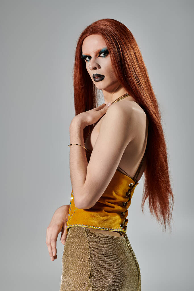 drag queen pitkät punaiset hiukset ja rohkea meikki poseeraa lumoava kulta asu. - Valokuva, kuva