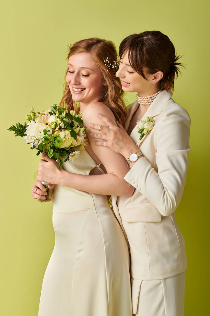 Duas noivas em trajes de casamento branco ficar juntos, abraçando, em um pano de fundo verde. - Foto, Imagem