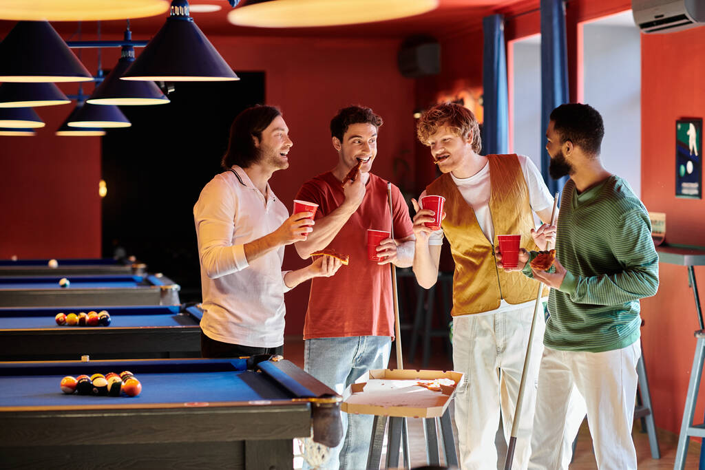 Vrienden staan rond een pooltafel, drinken in de hand, in een informele setting. - Foto, afbeelding