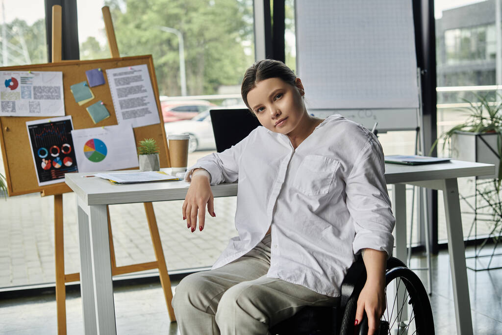 A young businesswoman in a wheelchair works at a desk in a modern office. - Photo, Image