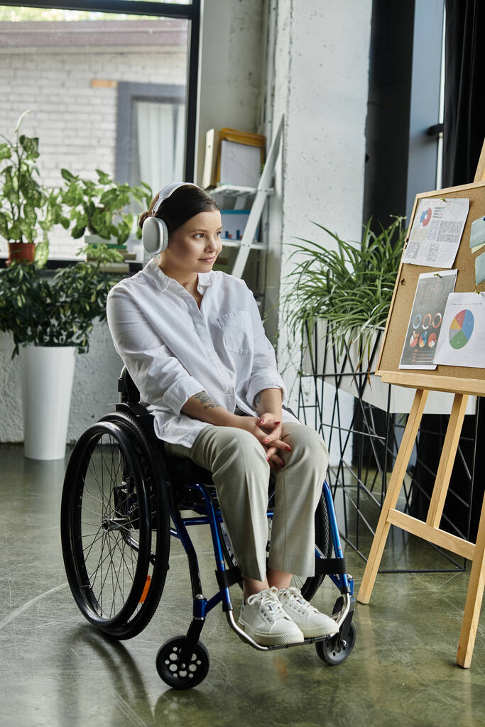 Молодая предпринимательница с ограниченными возможностями сидит в инвалидном кресле и работает в современном офисе, демонстрируя включение на рабочем месте. - Фото, изображение