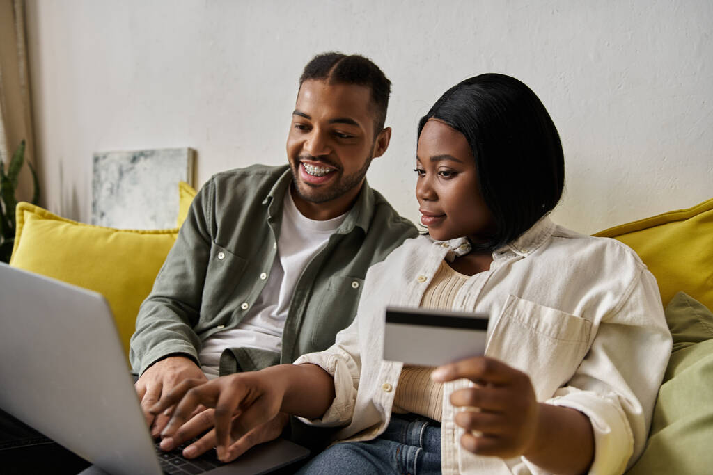 Milující afroameričtí pár obchody on-line společně doma, pomocí notebooku a kreditní karty. - Fotografie, Obrázek