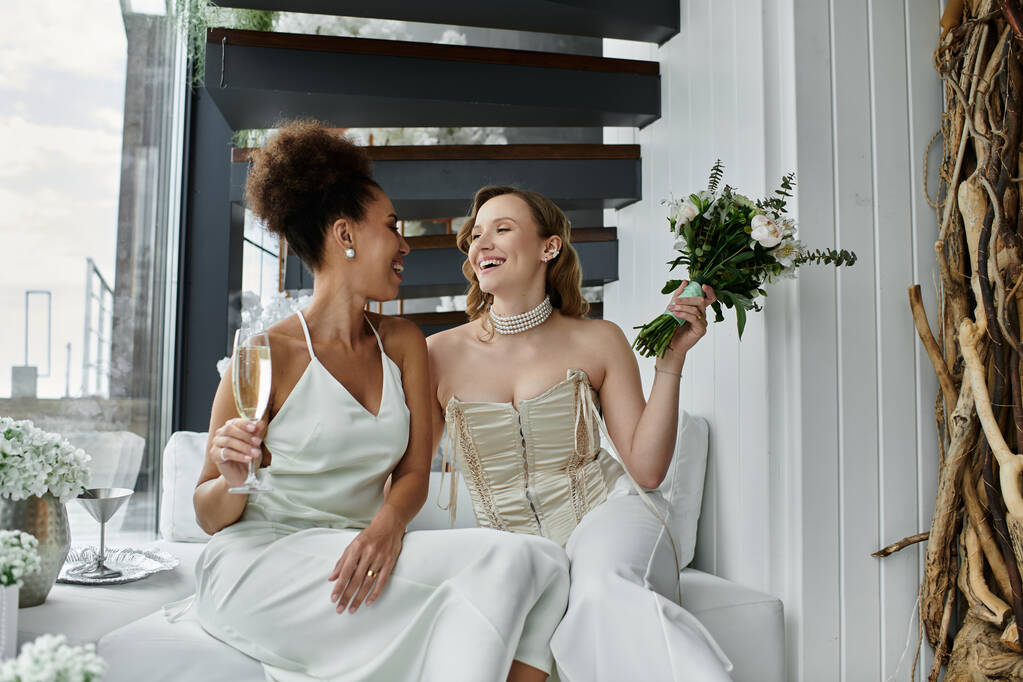 Dvě nevěsty slaví svatbu sklenicí šampaňského a kyticí květin. - Fotografie, Obrázek