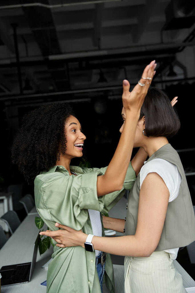 Due donne in ufficio celebrano insieme un successo, braccia alzate nella gioia. - Foto, immagini