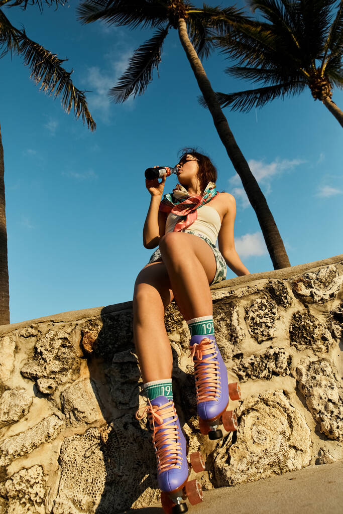 A young woman in sunglasses and a stylish outfit enjoys a break from roller skating in Miami. - Photo, Image