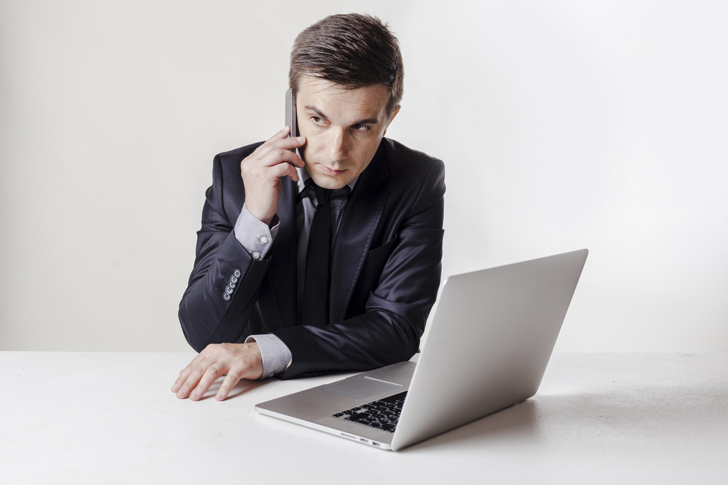 Immagine ravvicinata di uomo d'affari multitasking utilizzando un computer portatile e un telefono cellulare
 - Foto, immagini