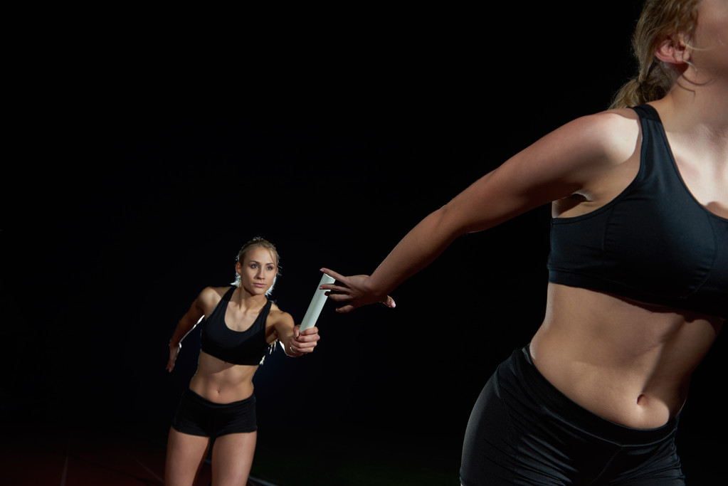 sportowe biegaczy przekazując pałeczkę sztafety - Zdjęcie, obraz
