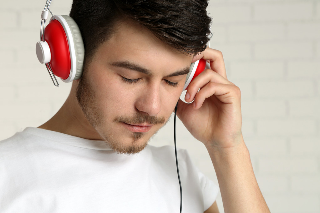 Komea nuori mies kuuntelee musiikkia tiiliseinällä tausta
 - Valokuva, kuva
