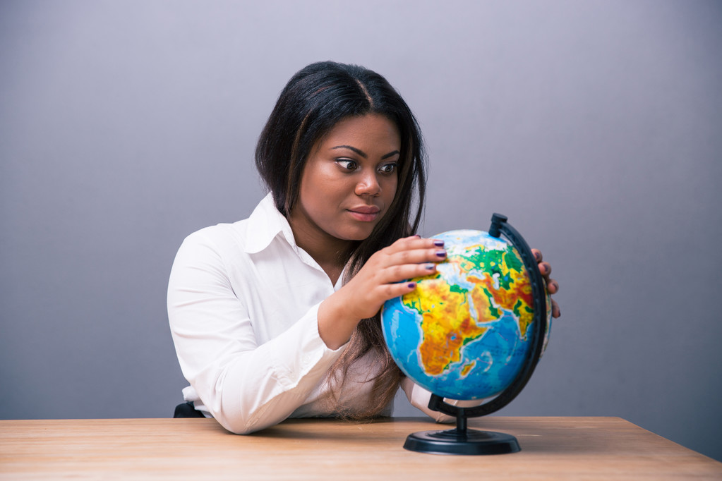 Африканская деловая женщина сидит за столом с глобусом
 - Фото, изображение