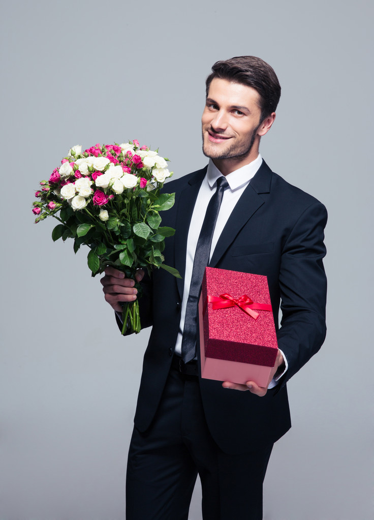 Красивий бізнесмен з квітами і подарунковою коробкою
 - Фото, зображення