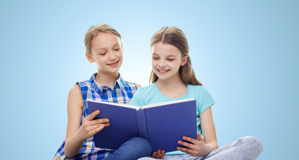 két vidám fiatal lányok könyv olvasó felső kék háttér - Fotó, kép