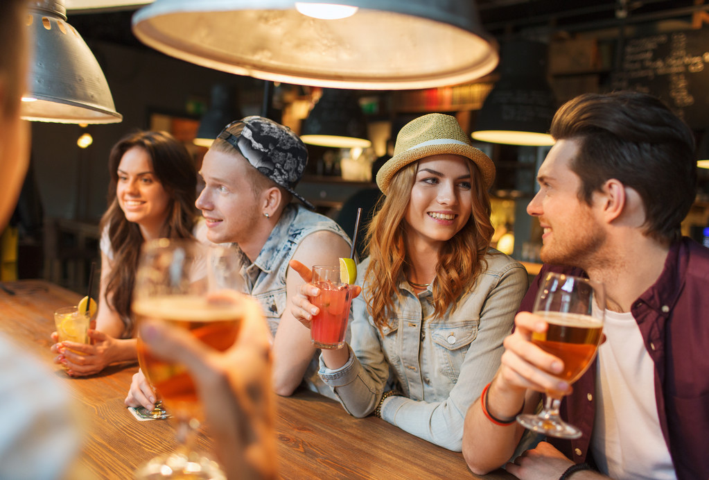 щасливі друзі з напоями розмовляють в барі або пабі
 - Фото, зображення