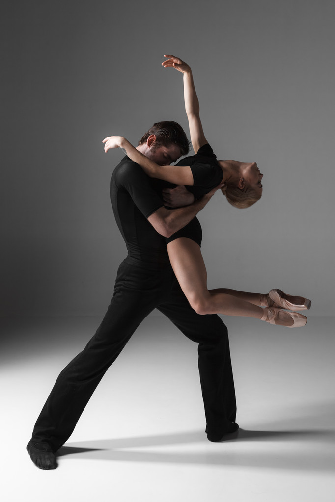 zwei junge moderne Balletttänzerinnen auf grauem Studiohintergrund  - Foto, Bild