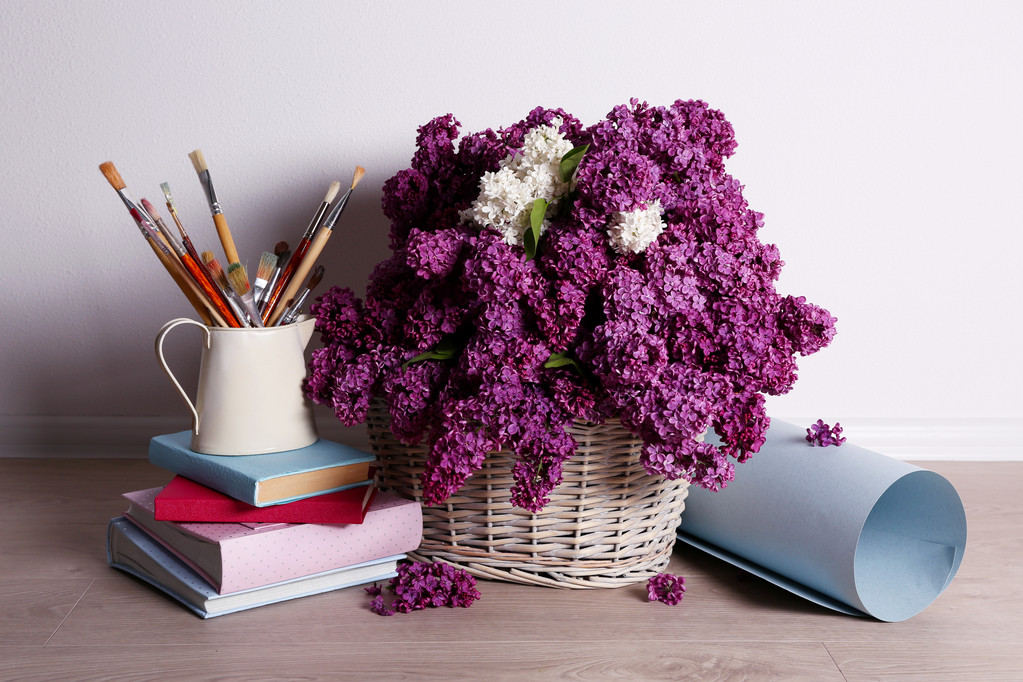 Beautiful lilac flowers on basket on floor in room close-up - Photo, Image