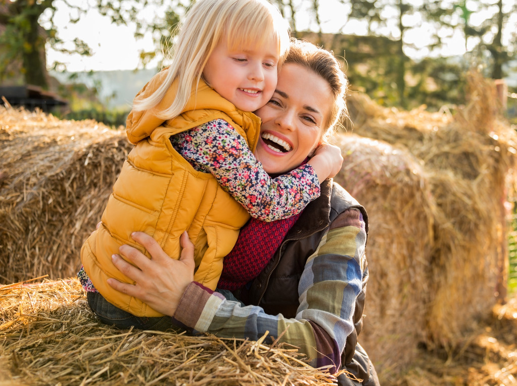 Portrait of happy mother and child hugging while on haystack - Photo, Image