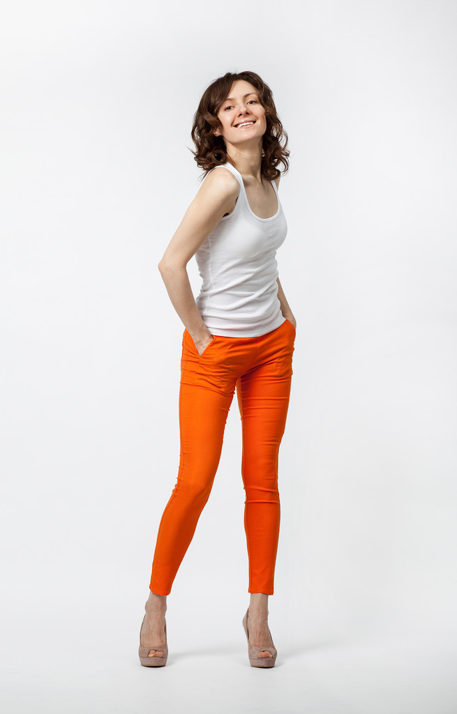 Щаслива усміхнена молода жінка в помаранчевих штанях позує на нейтральну спину
 - Фото, зображення