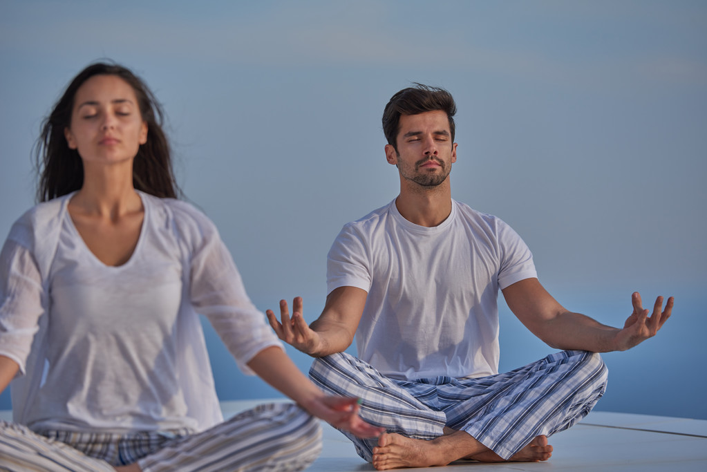 Young couple practicing yoga at home terrace - Photo, Image