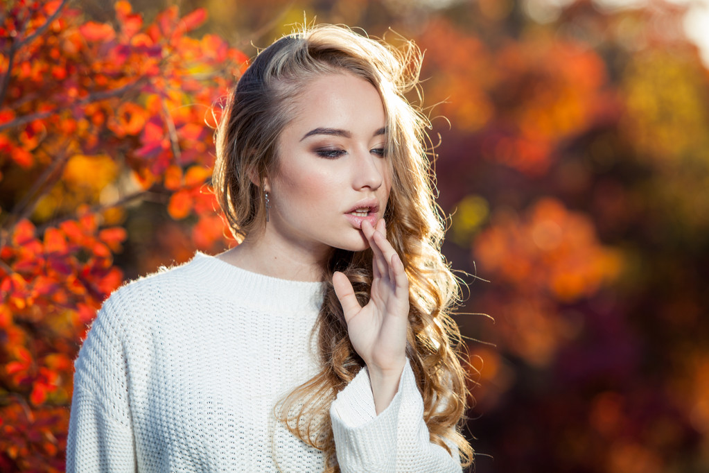 hermosa joven con el pelo rizado sobre un fondo de hojas de otoño rojas y amarillas
 - Foto, Imagen