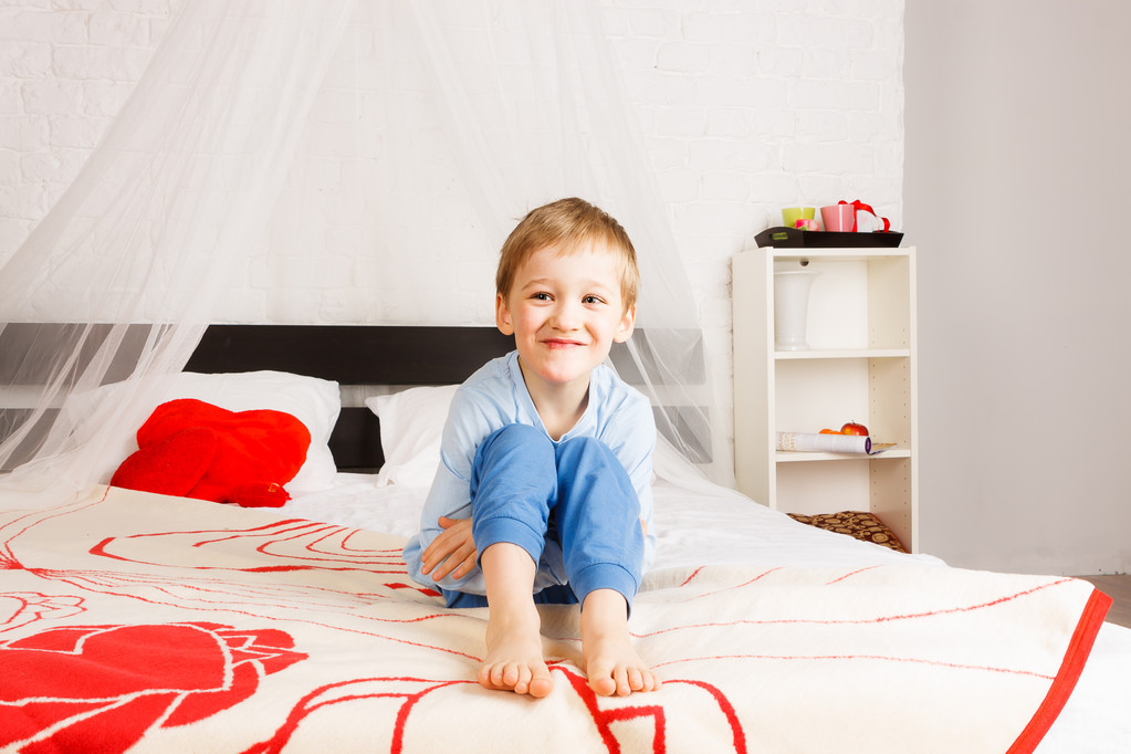 Smiling boy sitting on parents bed - Photo, Image