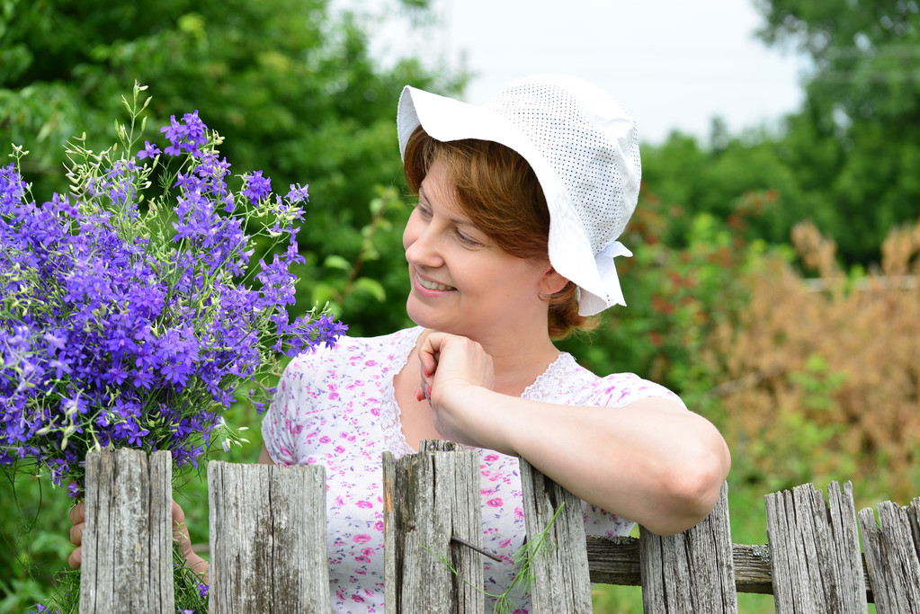 Žena s květy u dřevěného plotu v obci - Fotografie, Obrázek