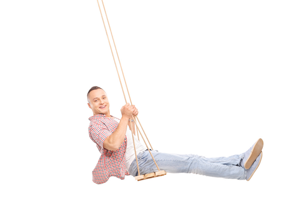 Delighted young man swinging on a wooden swing  - Fotoğraf, Görsel