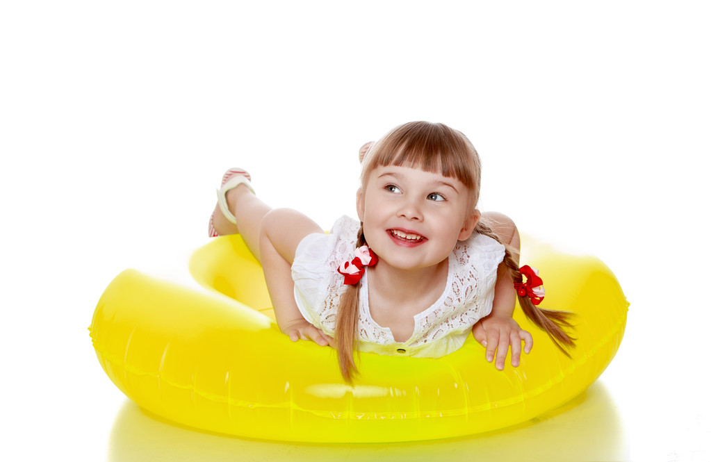 Heureuse fille blonde joyeuse avec des queues de cochon est sur un gonflable jaune
 - Photo, image