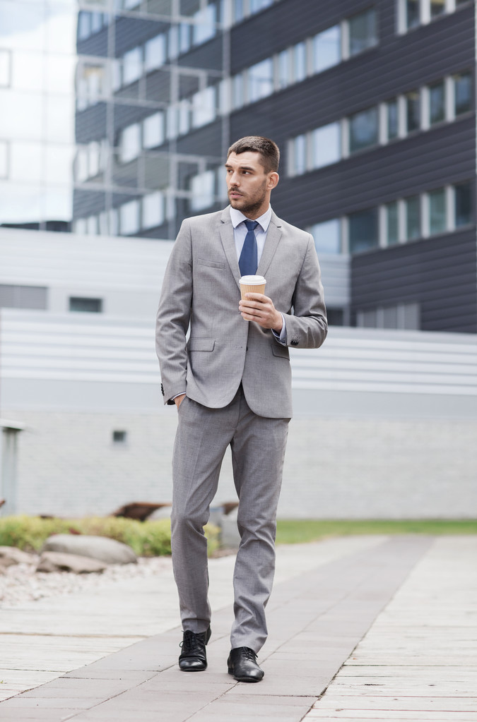 young serious businessman with paper cup outdoors - Photo, Image