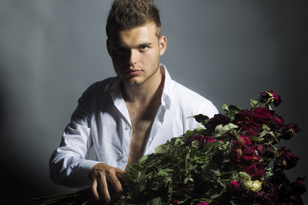 Porträt eines hübschen Mannes mit Blumen im Atelier - Foto, Bild