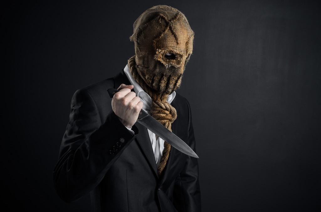 Medo e tema de Halloween: um assassino brutal em uma máscara segurando uma faca em um fundo escuro no estúdio
 - Foto, Imagem