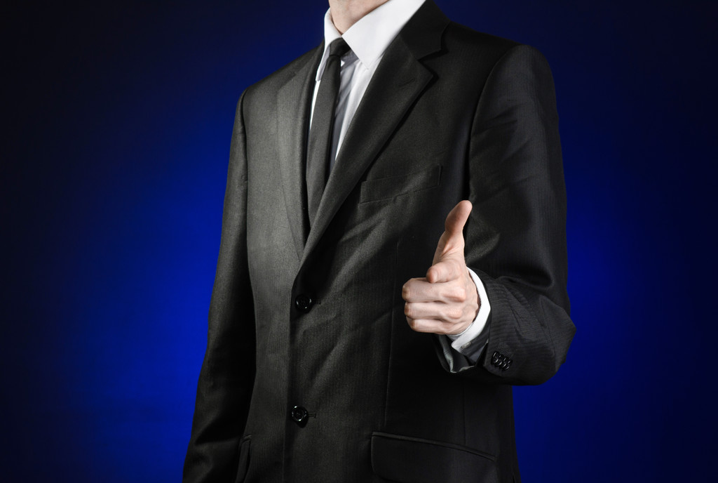 Businessman and gesture topic: a man in a black suit and white shirt shows his hand forward on a dark blue background in studio isolated - Fotoğraf, Görsel