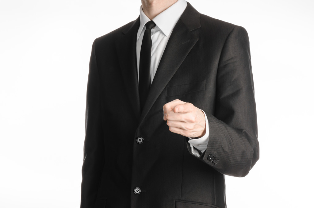 Businessman and gesture topic: a man in a black suit with a tie shows his hand forward isolated on white background in studio - Fotografie, Obrázek