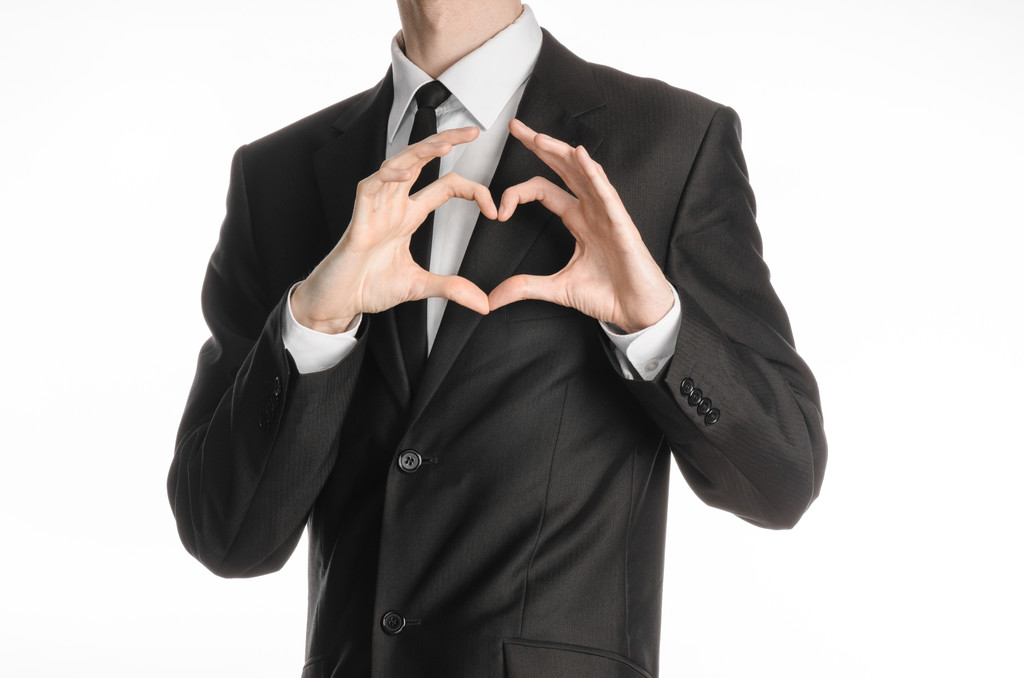 Tópico de homem de negócios e gesto: um homem de terno preto com um laço mostrando um sinal do coração e mãos de amor em um fundo branco isolado no estúdio
 - Foto, Imagem