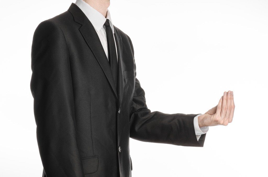 Бизнесмен и тема жеста: человек в черном костюме и галстуке, держащий перед собой руку и показывающий щепотку на изолированном белом фоне в студии
 - Фото, изображение