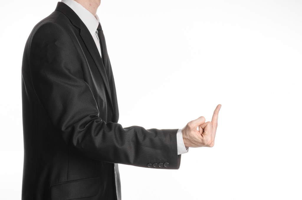 Businessman and gesture topic: a man in a black suit showing middle finger on an isolated white background in studio - Foto, afbeelding