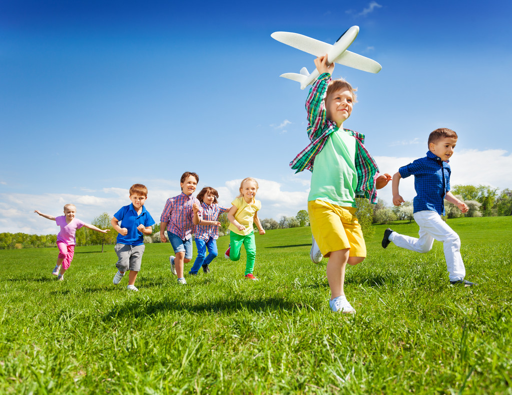 niños corriendo con niño sosteniendo el avión
 - Foto, Imagen