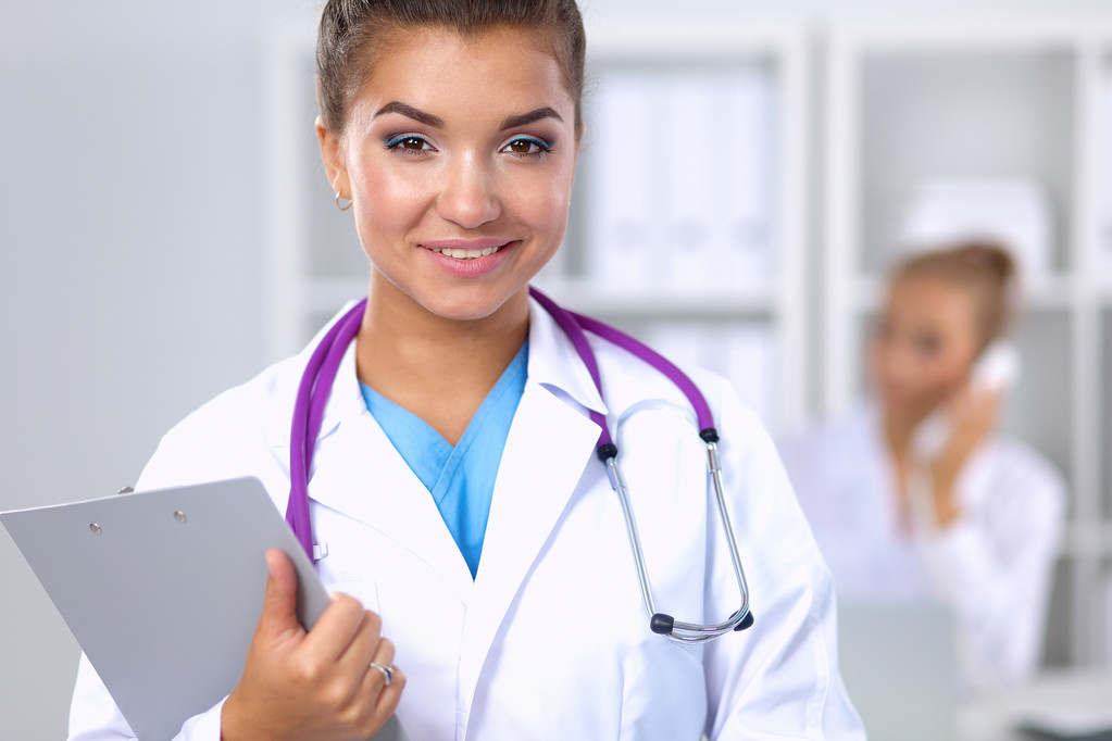 Hymyilevä naislääkäri, jolla on univormu ja joka seisoo sairaalassa - Valokuva, kuva