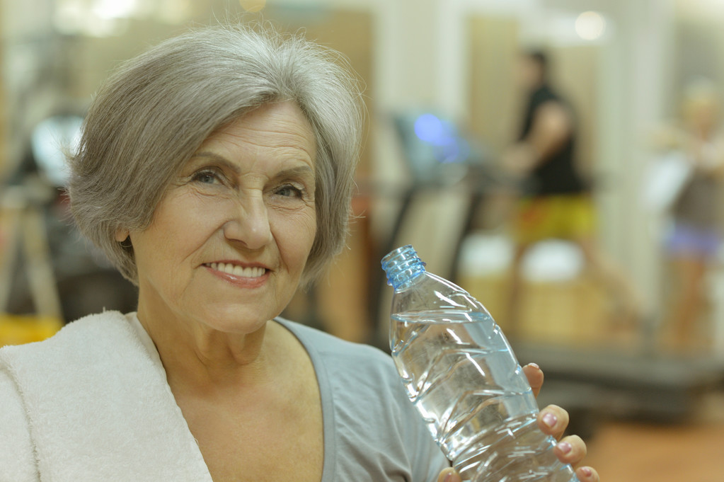 Mujer mayor bebiendo agua en el gimnasio
 - Foto, imagen