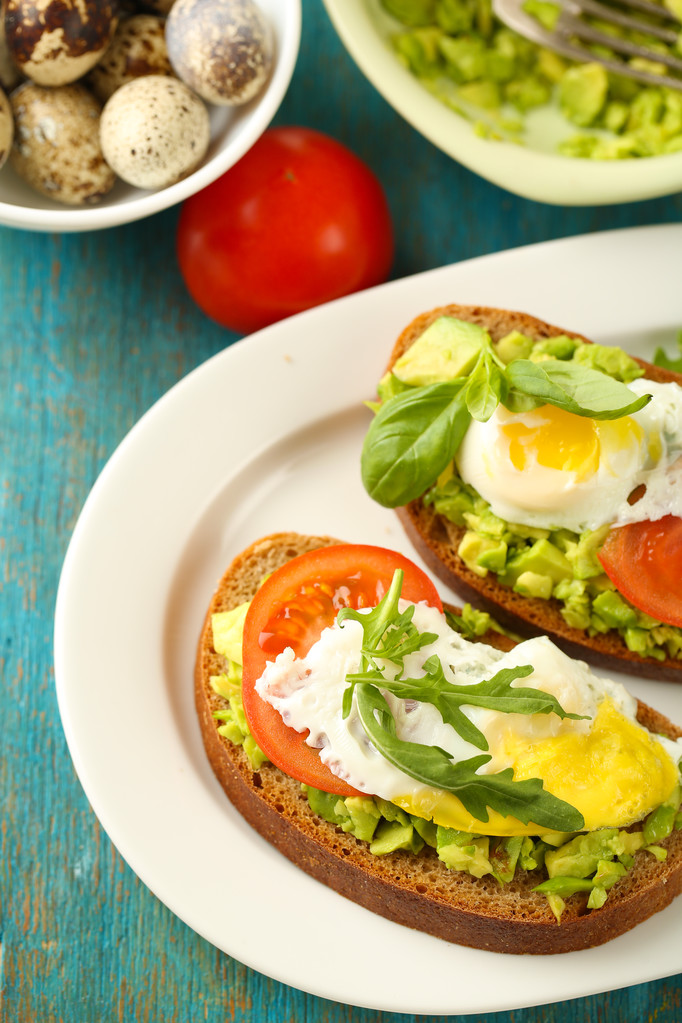 Tasty sandwiches with egg, avocado and vegetables on plate, on wooden background - Photo, Image