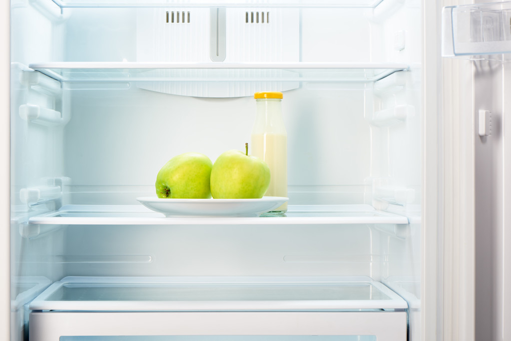 Apples on white plate with bottle of yoghurt in refrigerator - Photo, Image