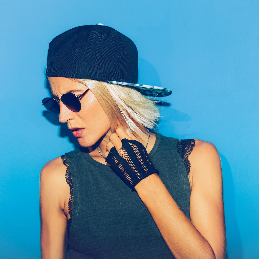 дівчина стоїть на синій стіні в стильних окулярах і кепці. міський стиль
 - Фото, зображення