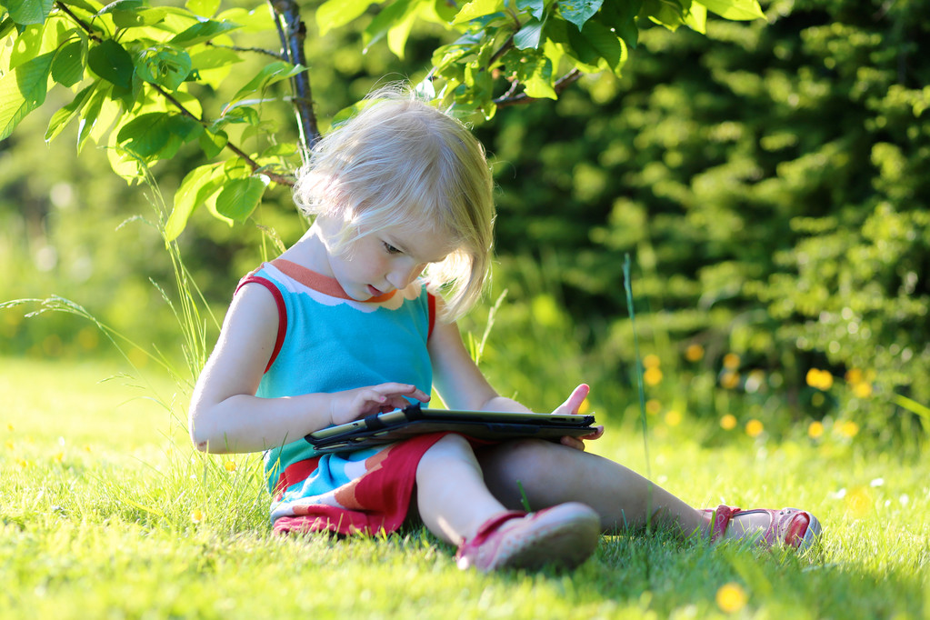 Toddler girl using tablet pc outdoors - Fotó, kép