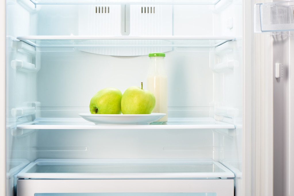 Dwa jabłka na płytkę i butelki jogurtu w lodówce - Zdjęcie, obraz