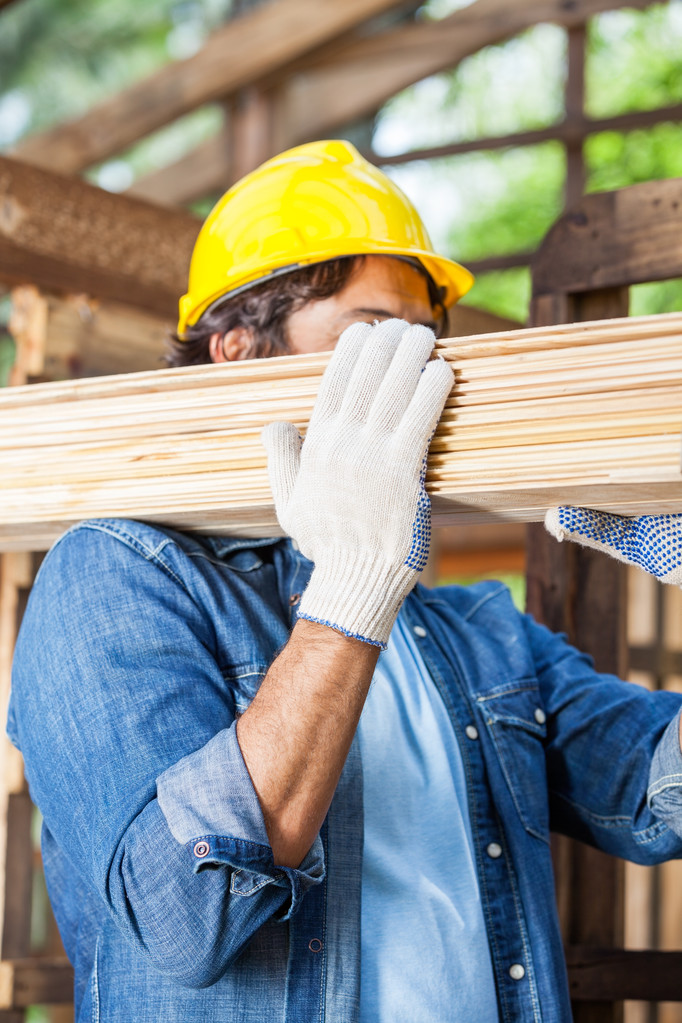 Trabajador llevando tablones de madera en el sitio
 - Foto, imagen