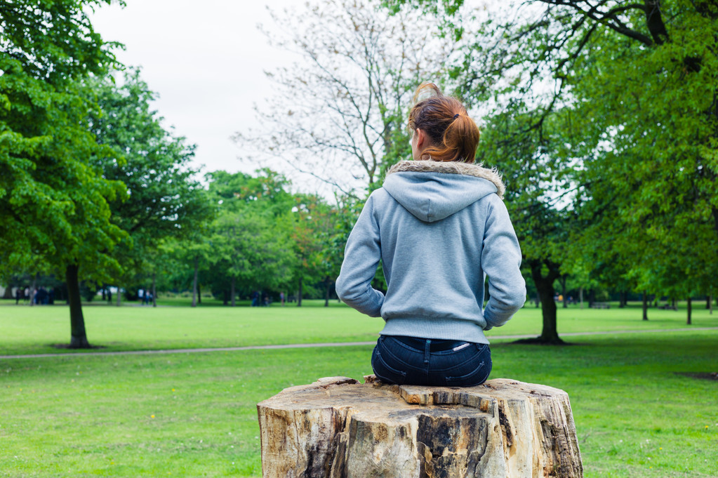 Giovane donna seduta sul tronco d'albero nel parco
 - Foto, immagini