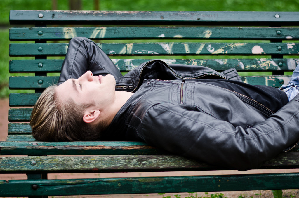 Attractive blue eyed, blond young man laying on park bench - Foto, Imagem