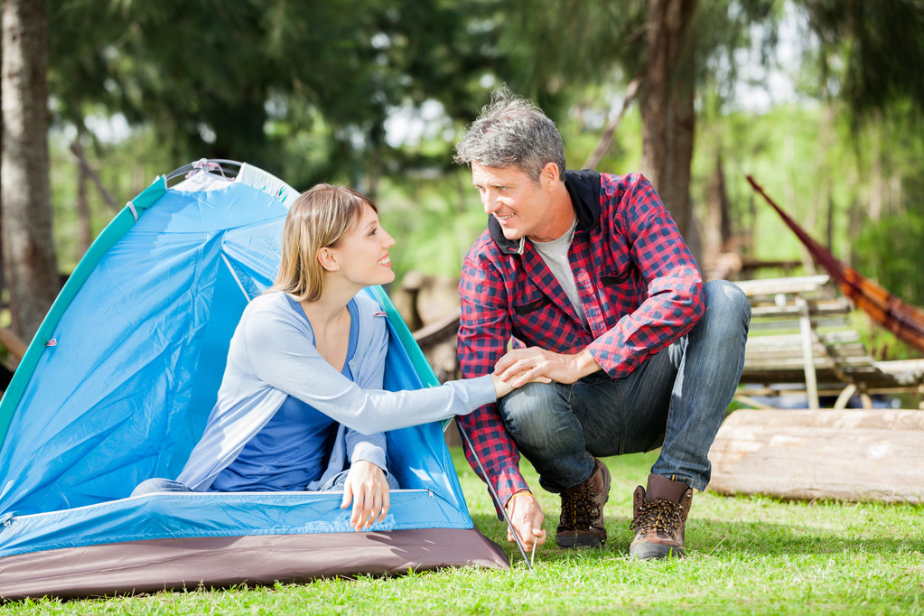Para trzymając się za ręce podczas konfigurowania namiot w parku - Zdjęcie, obraz
